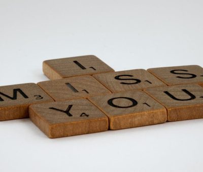 Close-up of Scrabble tiles spelling 'I Miss You' on a white surface with ample copy space.